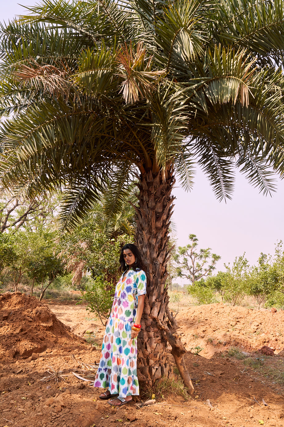 model wearing an ikat maxi dress rom kleed in 100% ikat resting under a palmtree