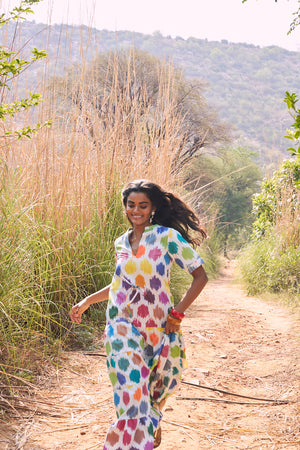 editorial photo of model wearing anouk maxi dress by kleed in 100% cotton ikat. Running in the countryside. 