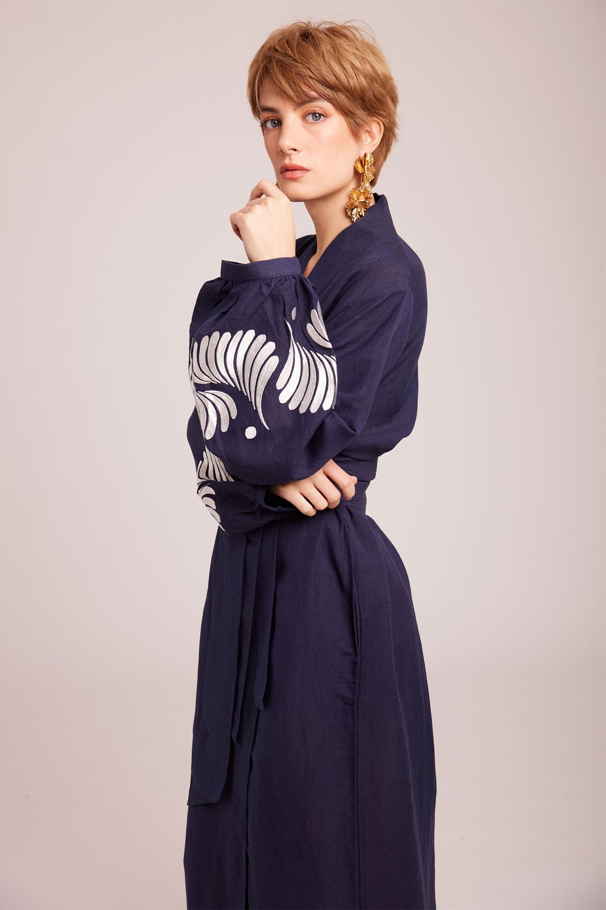 Woman wearing Kleed Blue Kandy Kimono in 100% cotton dark navy blue with white floral embroidery on cuffs full length studio