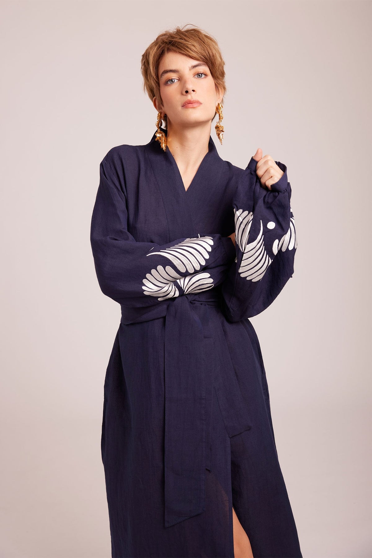 Woman seated wearing Kleed Blue Kandy Kimono in 100% cotton dark navy blue balloon sleeves white floral embroidered cuffs