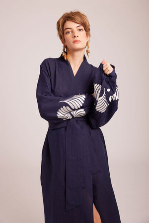 Woman seated wearing Kleed Blue Kandy Kimono in 100% cotton dark navy blue balloon sleeves white floral embroidered cuffs