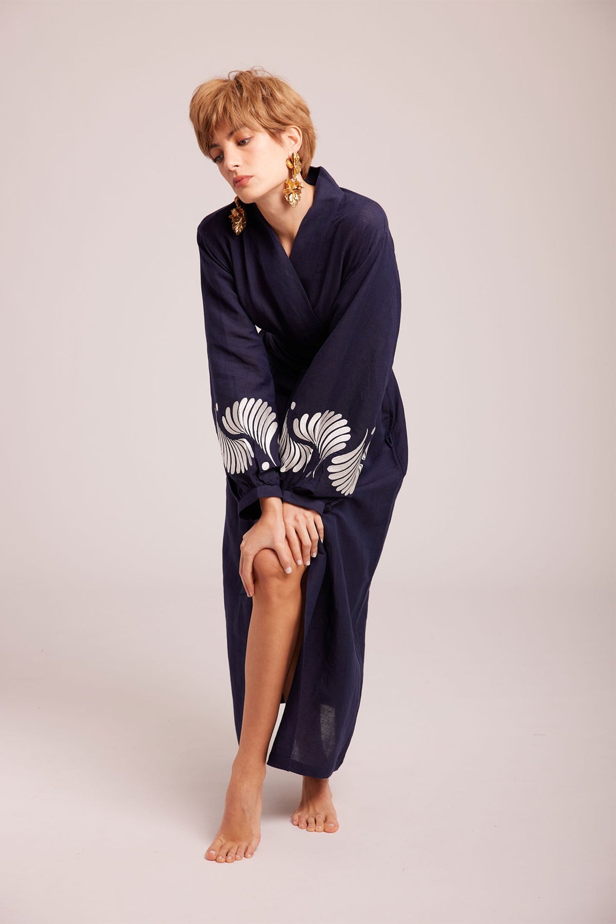 Woman walking wearing Kleed Blue Kandy Kimono in 100% cotton dark navy blue white floral embroidery on cuffs studio
