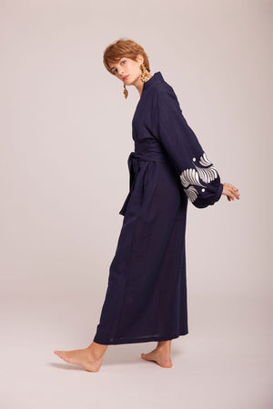 oman wearing Kleed Blue Kandy Kimono in 100% cotton dark navy blue with white floral embroidery on balloon sleeve cuffs side view