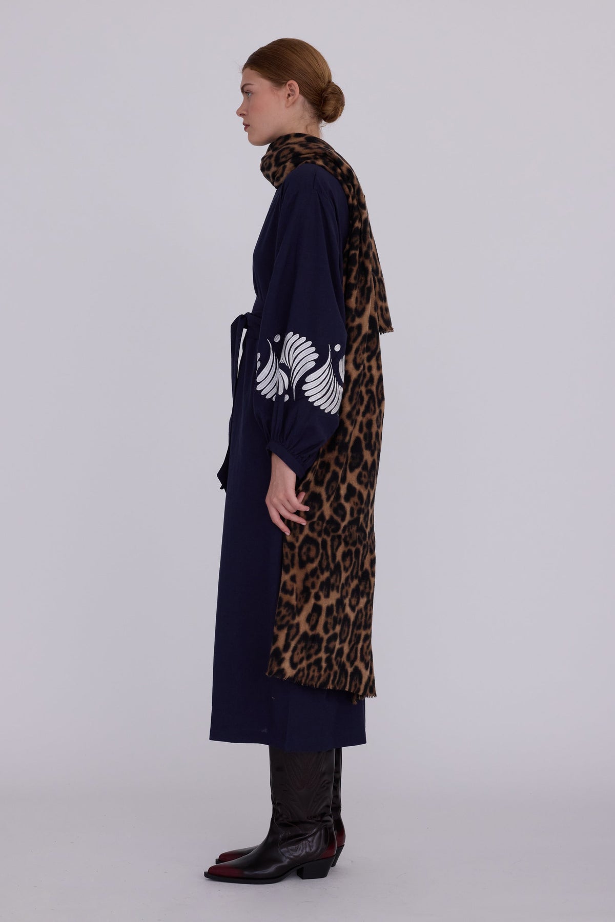 Woman wearing Kleed Blue Kandy Kimono in 100% cotton dark navy blue white floral embroidered cuffs side view styled with leopard print scarf and cowboy boots