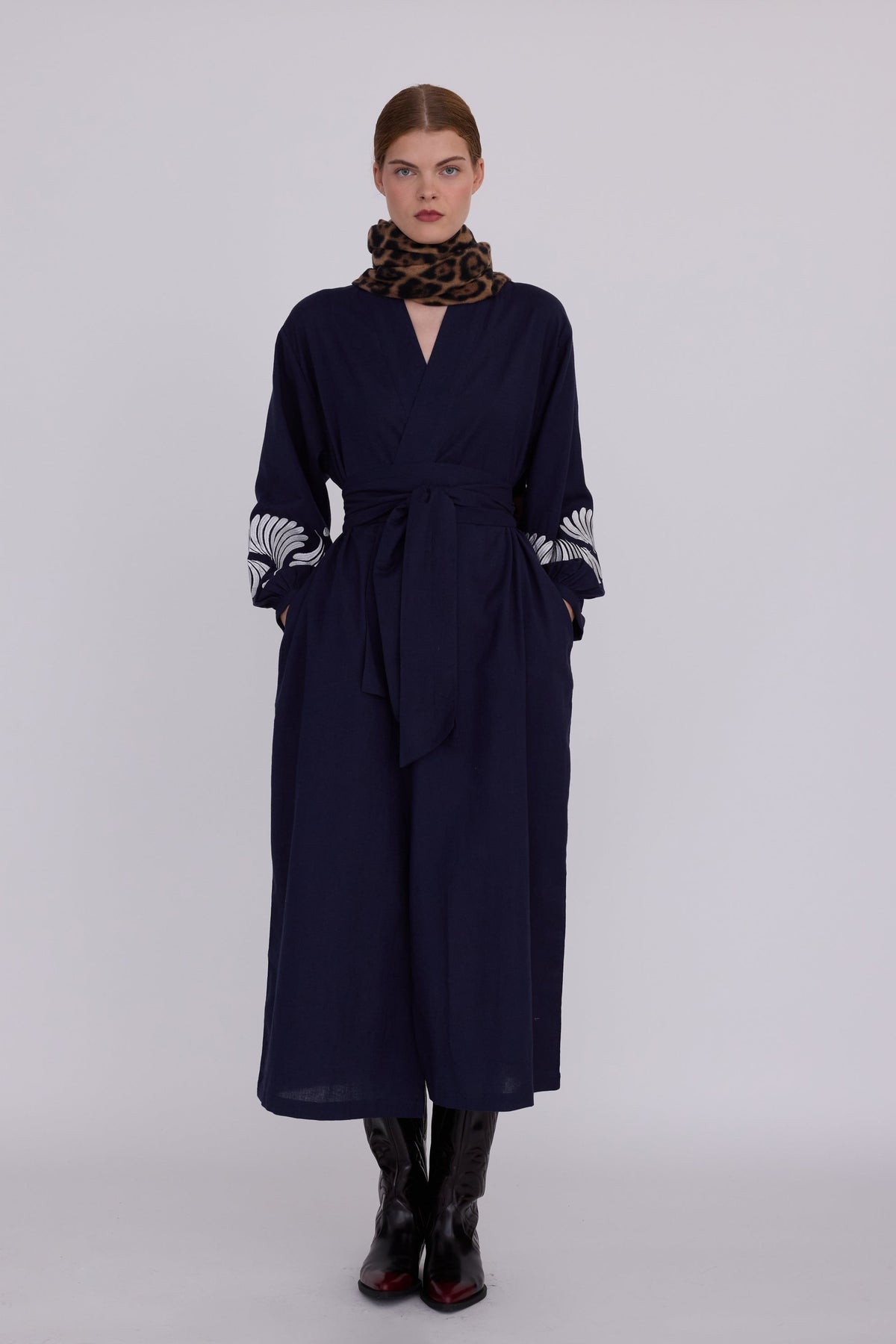 Woman wearing Kleed Blue Kandy Kimono in 100% cotton dark navy blue with white floral embroidery on balloon sleeve cuffs front view styled with leopard print scarf