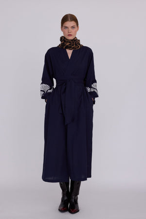 Woman wearing Kleed Blue Kandy Kimono in 100% cotton dark navy blue with white floral embroidery on balloon sleeve cuffs front view styled with leopard print scarf
