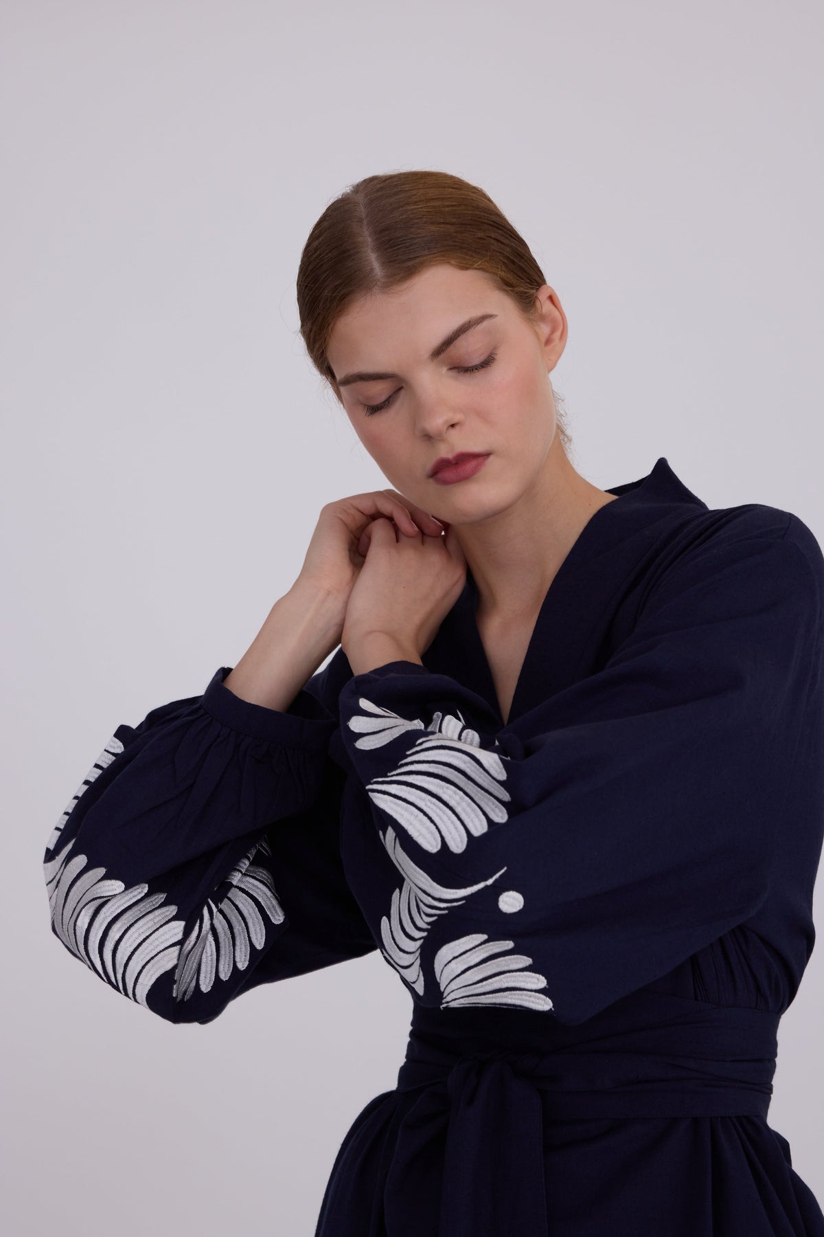 Close up of woman wearing Kleed Blue Kandy Kimono in 100% cotton dark navy blue with white floral embroidery detail on balloon sleeve cuffs