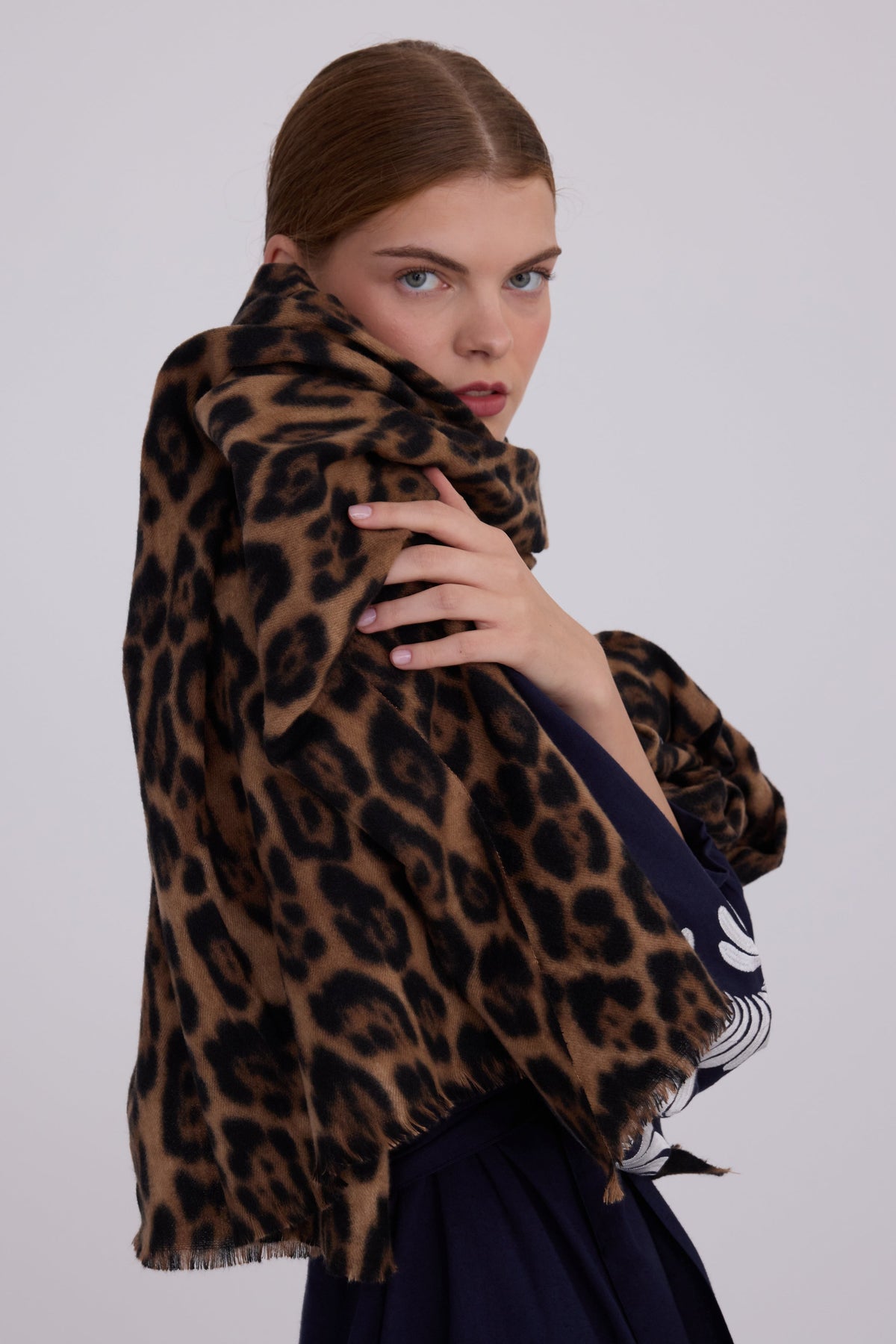 Woman wearing Kleed Blue Kandy Kimono in 100% cotton dark navy blue with white floral embroidered cuffs wrapped in leopard print scarf studio