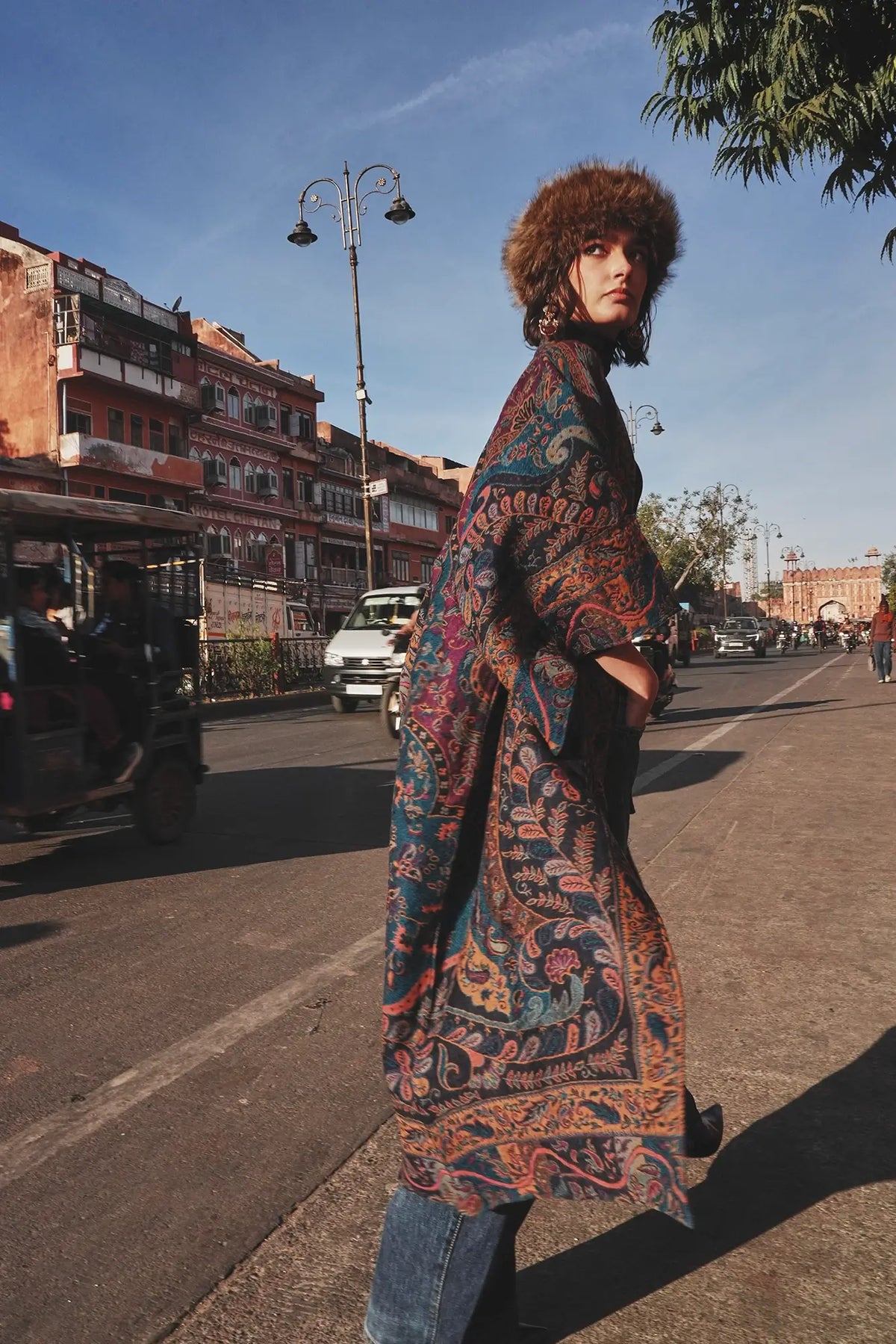 Woman wearing Kleed Fuchsia Paisley Kimono Coat in wool on a sunlit street, long paisley print coat with belt.