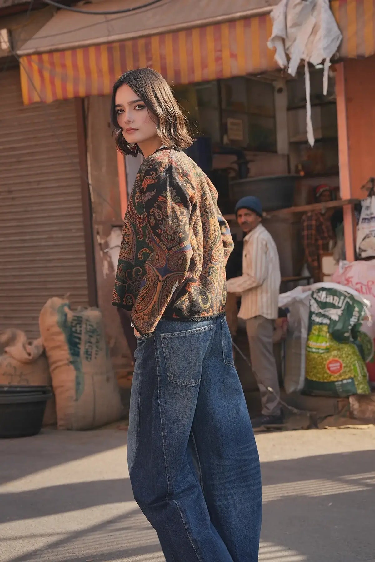 Kleed Green Oak Jacket in wool worn on a sunlit street, paisley print jacket styled with jeans and a white top.