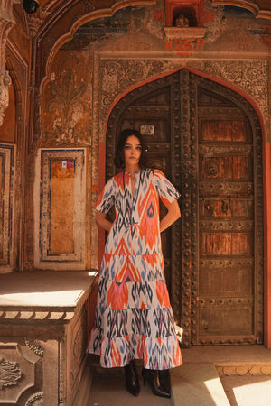 Full length view of a woman wearing the Kleed Tangerine Bikaner Maxi Dress in handloomed cotton ikat, photographed in front of an ornate carved wooden door