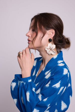 Close-up of model in profile wearing Kleed Turquoise Savannah Short Kimono in Ikat cotton with white floral statement earrings.