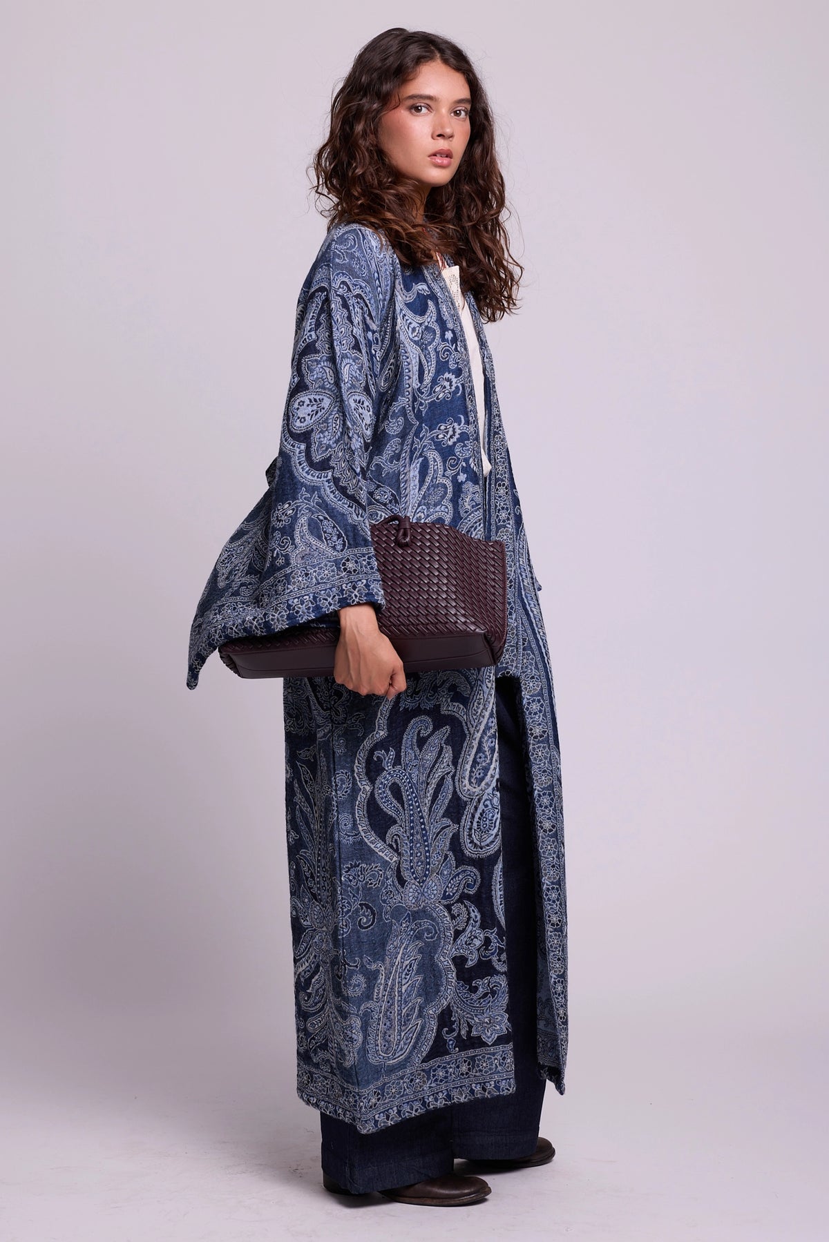 Kleed Blue Paisley Kimono Coat in wool with paisley print, styled with black trousers and a woven leather tote.