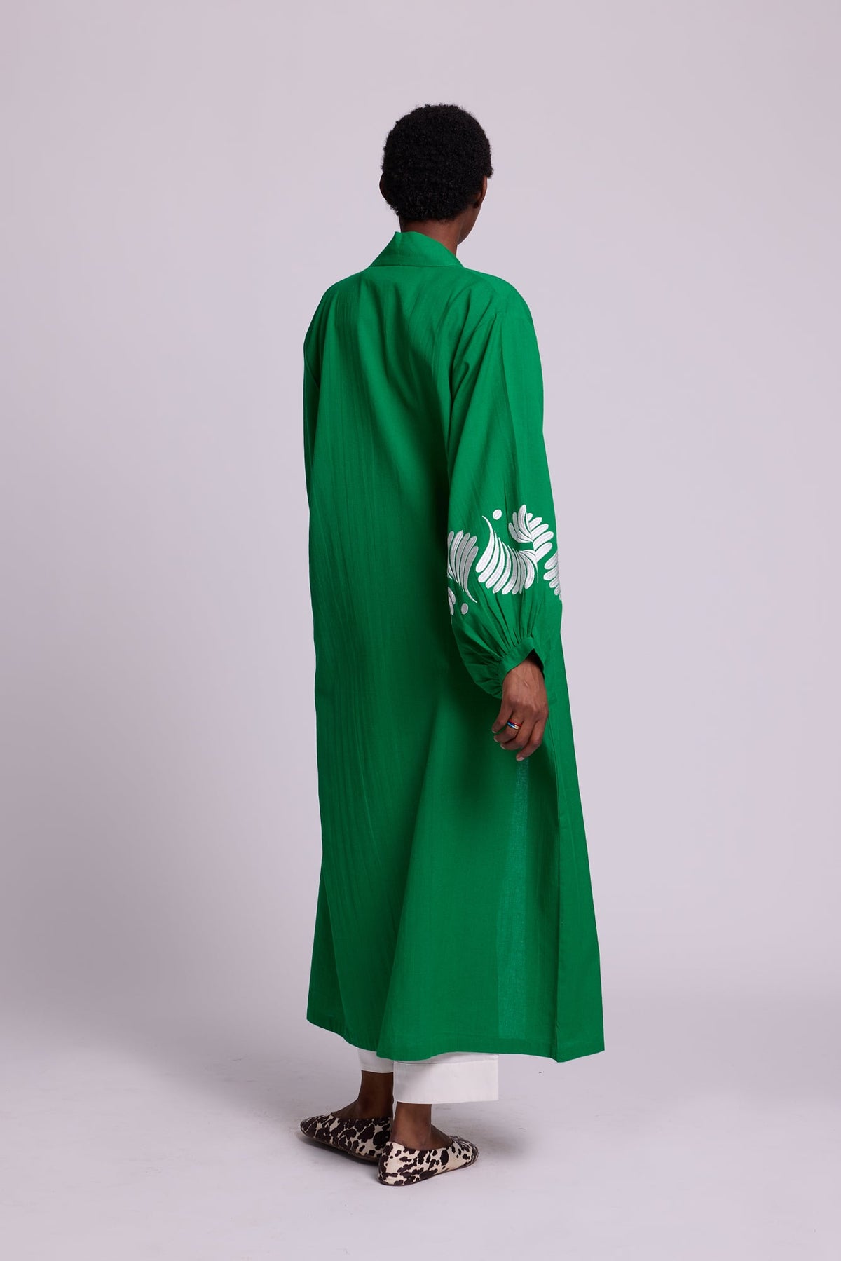 Back side view of a woman wearing the Kleed Green Kandy Kimono in 100% cotton showing the full length silhouette and white floral embroidered sleeve detail