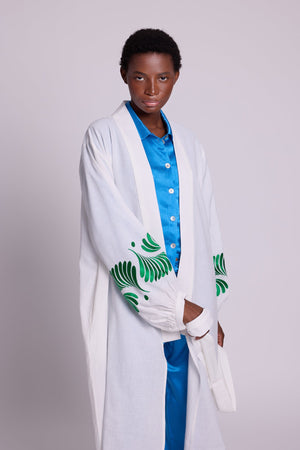 Woman wearing Kleed Light Kandy Kimono in white cotton with emerald green silk floral embroidery on the cuffs.