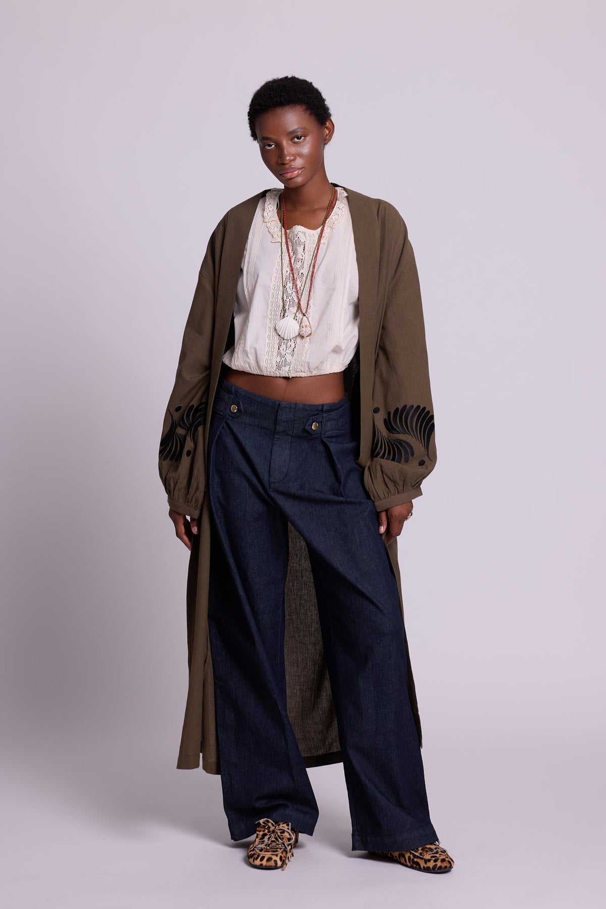 Kleed Olive Kandy Kimono in khaki cotton with black floral embroidered cuffs, styled with white top, jeans and animal print mules.
