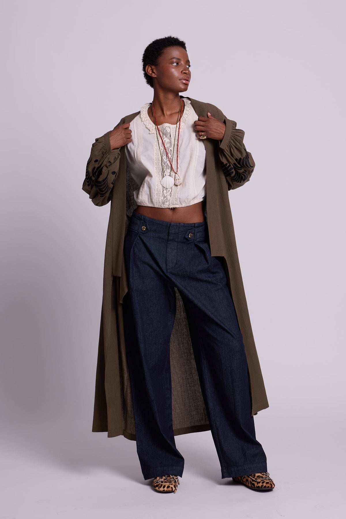 Front view of Kleed Olive Kandy Kimono in khaki cotton with black floral embroidered cuffs, styled with white top and dark jeans.