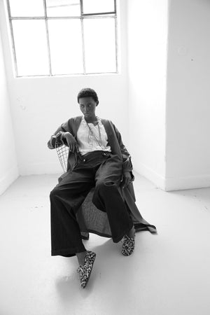Black and white editorial of Kleed Olive Kandy Kimono in khaki cotton with black floral embroidered cuffs.

