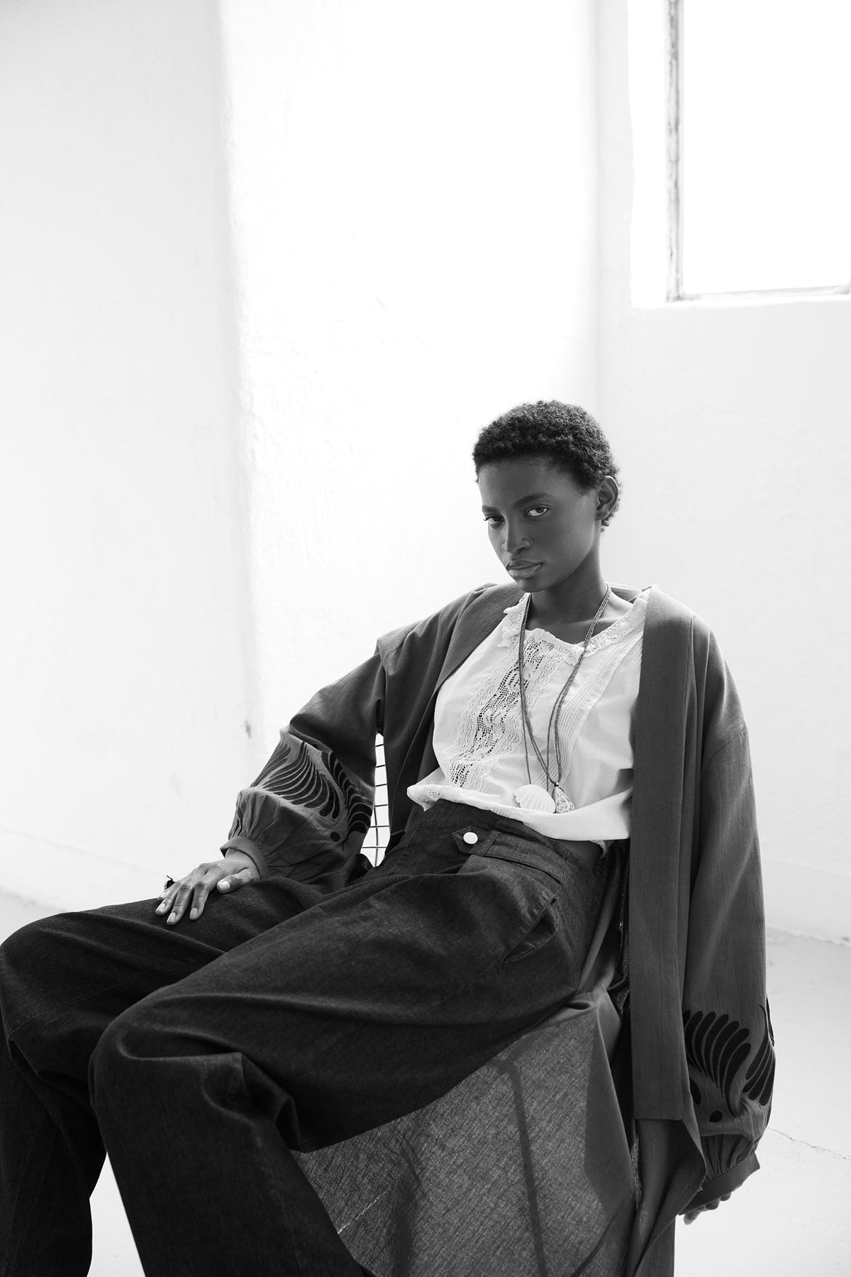 Black and white editorial of Kleed Olive Kandy Kimono in khaki cotton, full length view with shirt and trousers.
