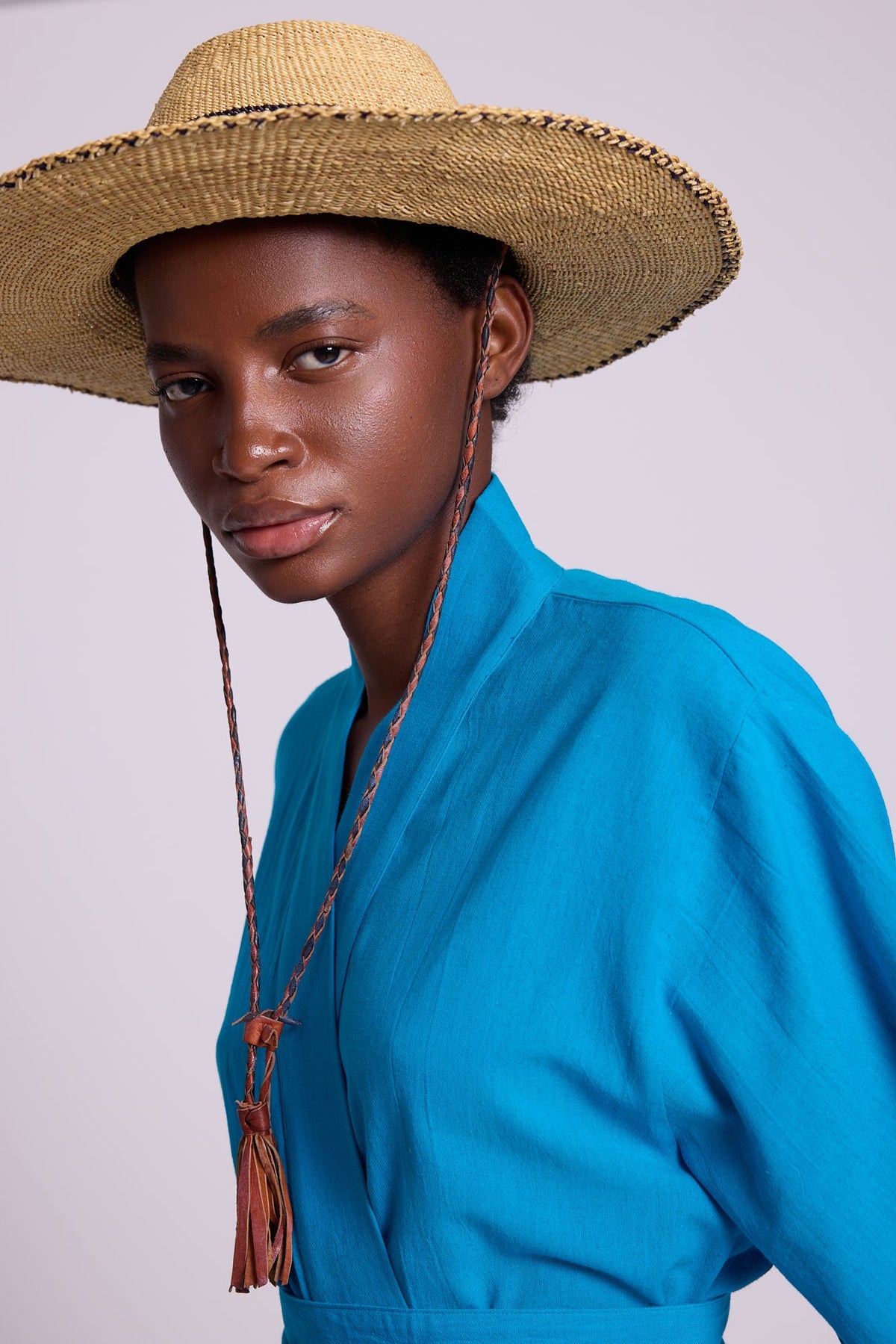 Close-up of Kleed Sky Blue Kandy Kimono in cotton, styled with a wide-brim straw hat and long necklace.
