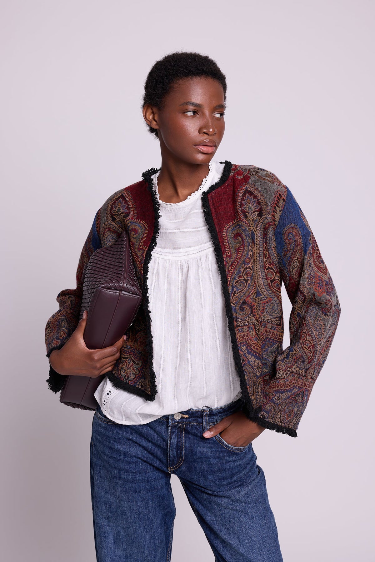 Kleed Blue Oak Jacket in pure wool with indigo and burgundy paisley print, styled with a white lace top, jeans and a leather clutch.