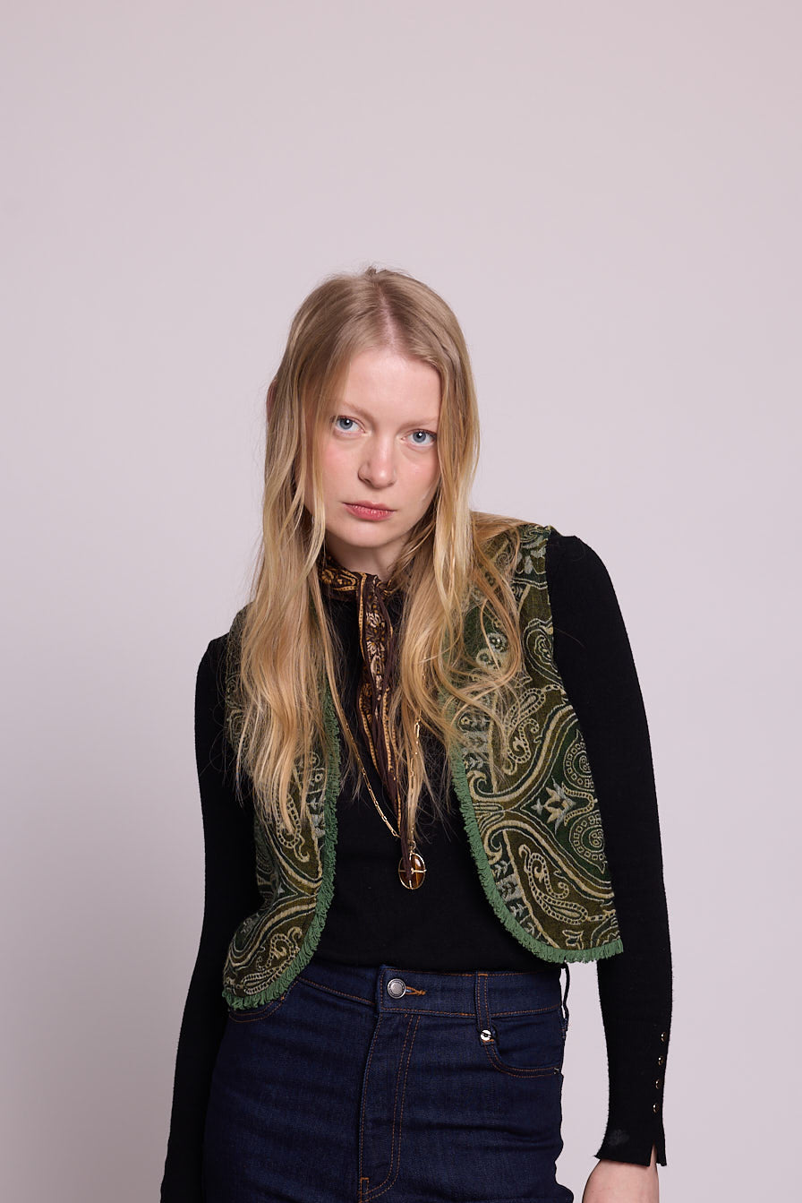 Full length front view of a woman wearing the Kleed Green Paisley Wool Vest over a black long sleeve top and dark wide leg jeans