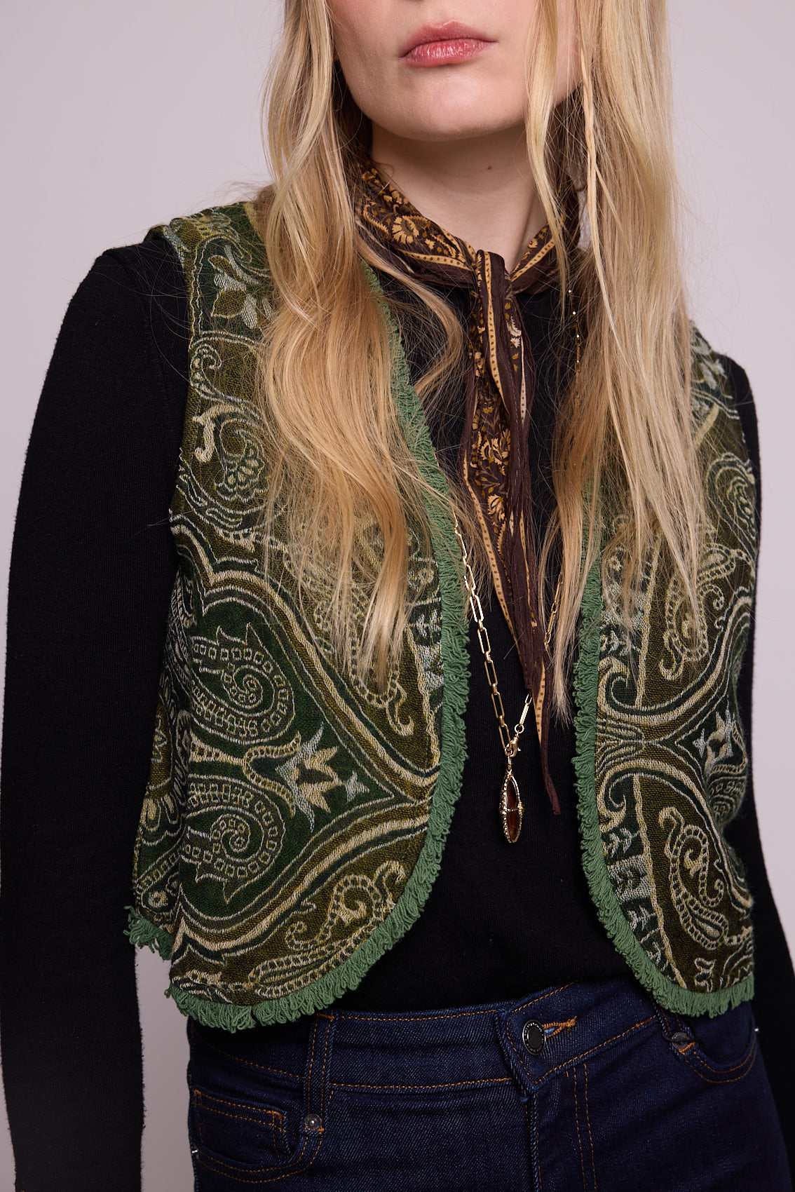 Front close up view of a woman wearing the Kleed Green Paisley Wool Vest over a black long sleeve top