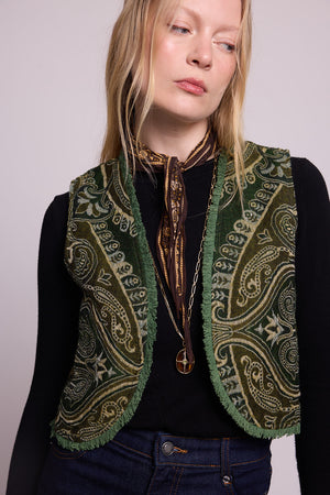 Close up of a woman wearing the Kleed Green Paisley Wool Vest over a black long sleeve top, styled with a neck scarf and gold pendant necklace