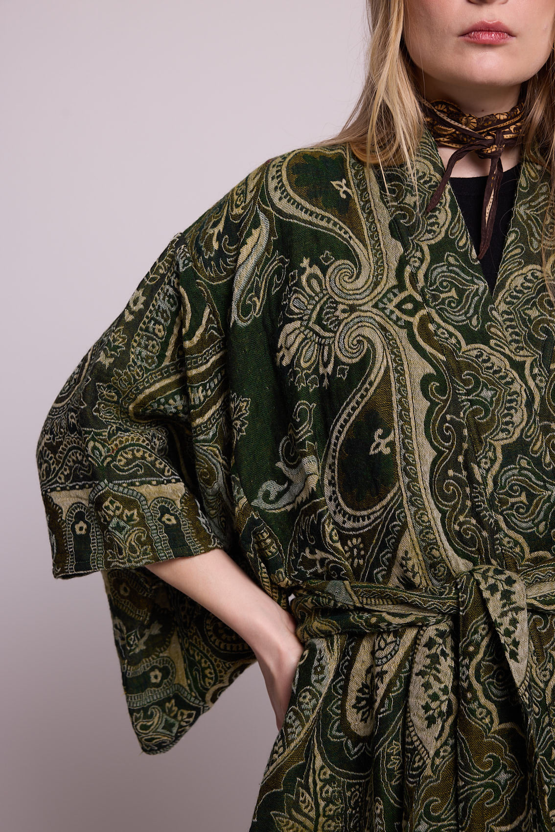 Close up front view of a woman wearing the Kleed Green Paisley Wool Kimono Coat in an outdoor street setting