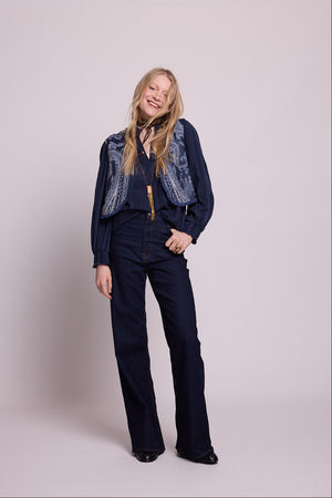 Full length side angle view of woman wearing the Kleed Blue Paisley Vest in navy wool with wide leg trousers