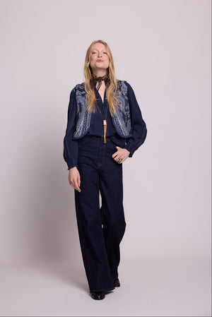 Woman wearing kleed's blue paisley vest
with a dark blue shirt against a light gray background 