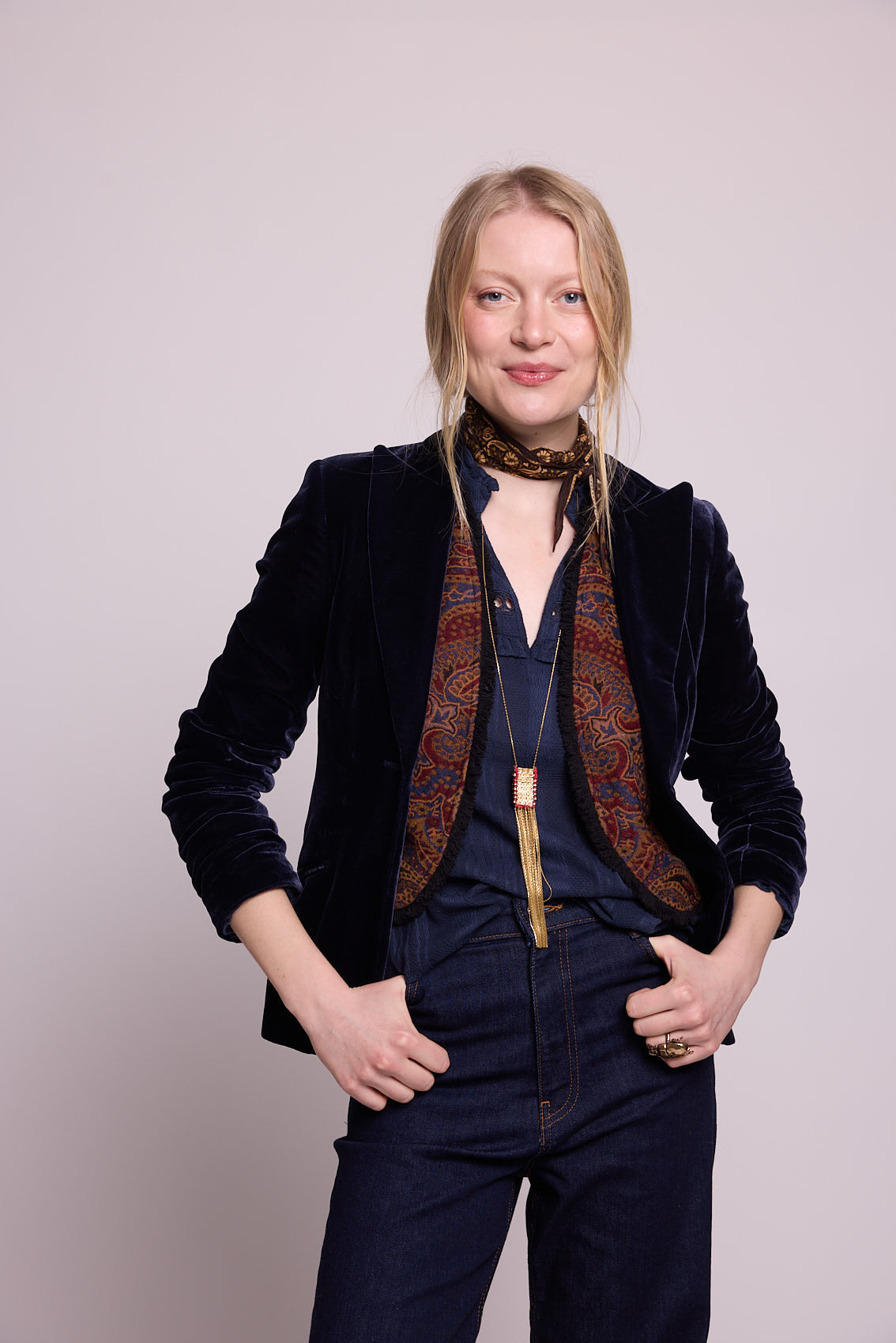 Model in three-quarter view wearing Kleed Blue Oak Vest in wool with paisley print, over a blue velvet blazer and trousers.