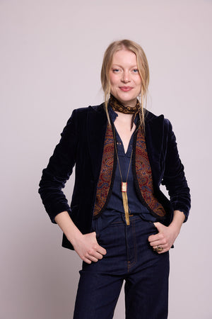 Model in three-quarter view wearing Kleed Blue Oak Vest in wool with paisley print, over a blue velvet blazer and trousers.