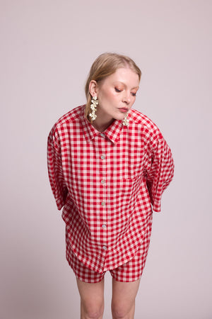 Full length front view of a woman wearing the Kleed Bhati Red Pyjama Set in red vichy cotton, showing the oversized shirt and matching shorts