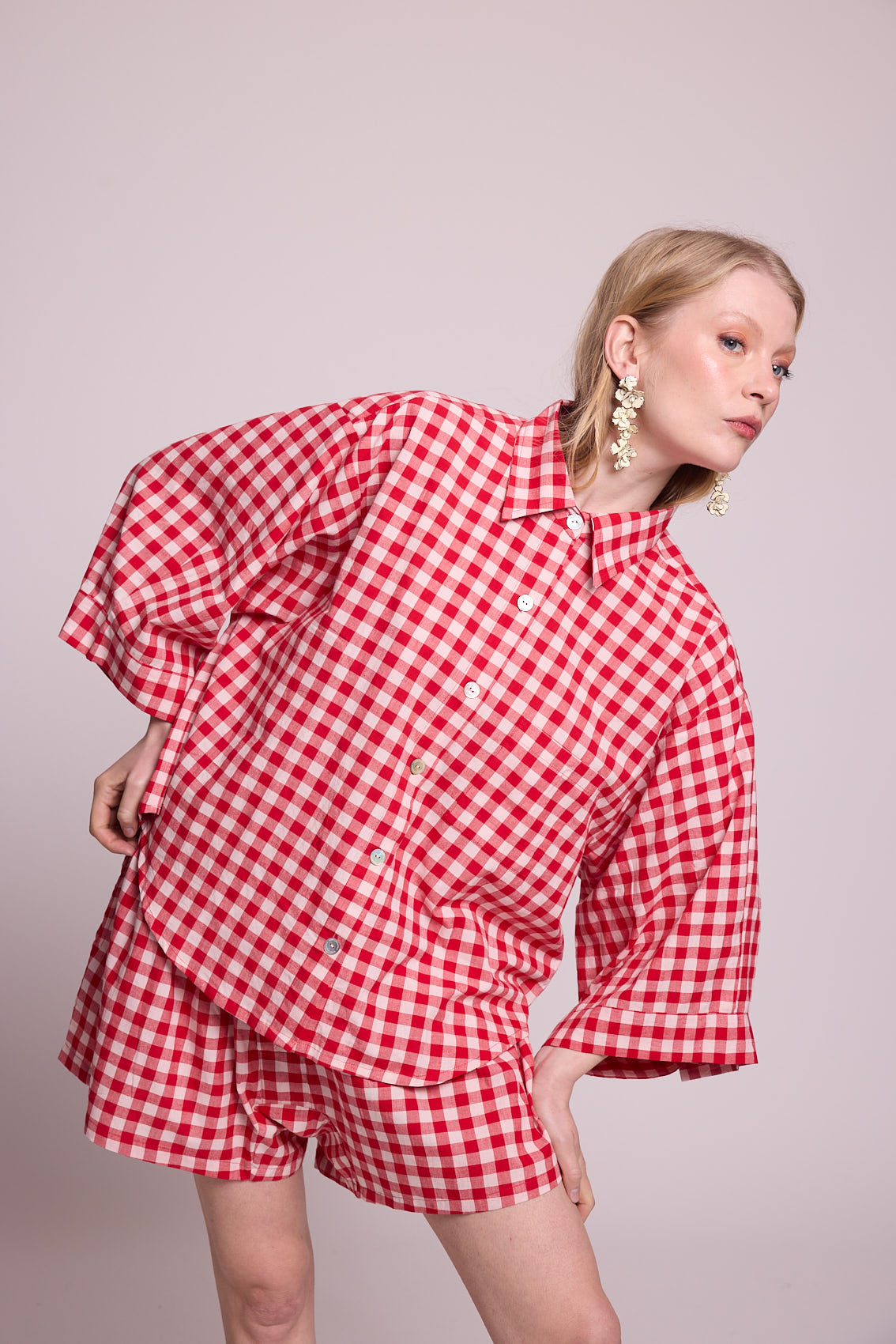 Close up of a woman wearing the Kleed Bhati Red Pyjama Set in red vichy cotton, featuring the oversized shirt with wide cuffs and dropped shoulders
