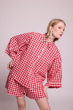 Close up of a woman wearing the Kleed Bhati Red Pyjama Set in red vichy cotton, featuring the oversized shirt with wide cuffs and dropped shoulders