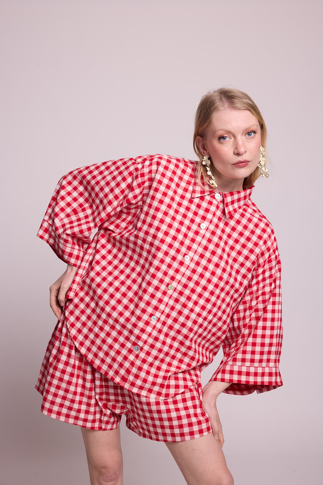 Full length alternative pose of a woman wearing the Kleed Bhati Red Pyjama Set in red vichy cotton, showing the oversized shirt and matching shorts