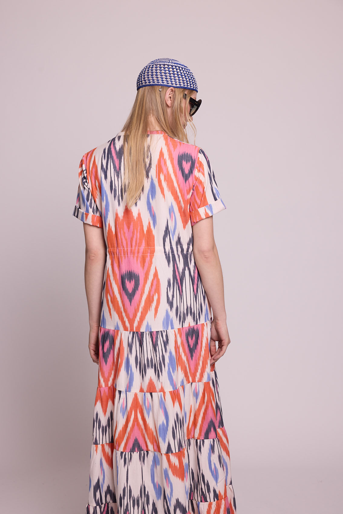 Full length side angle view of a woman wearing the Kleed Tangerine Bikaner Maxi Dress in handloomed cotton ikat, plain background