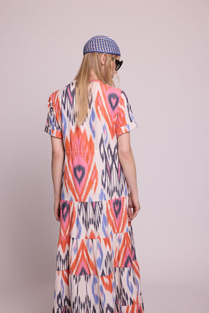 Full length side angle view of a woman wearing the Kleed Tangerine Bikaner Maxi Dress in handloomed cotton ikat, plain background