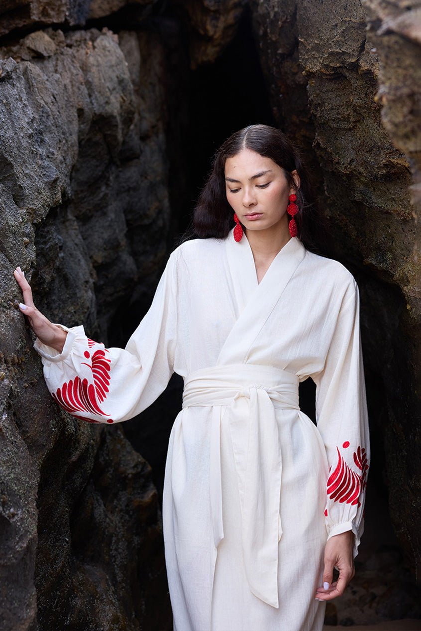 Woman wearing Kleed Natural Kandy Kimono in 100% cotton ivory white red floral embroidery on cuffs outdoor rocks editorial