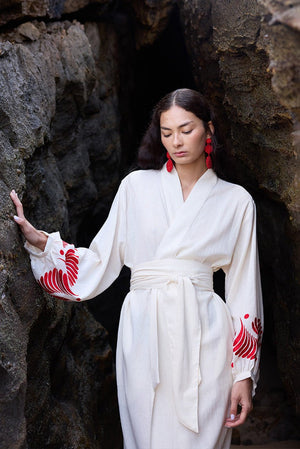 Woman wearing Kleed Natural Kandy Kimono in 100% cotton ivory white red floral embroidery on cuffs outdoor rocks editorial