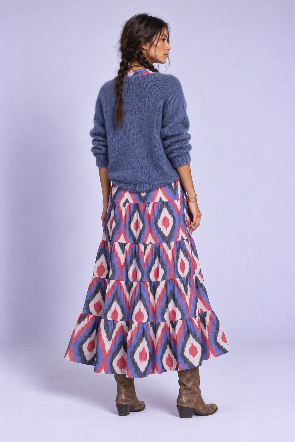 Back view of the Bahu Bikaner Dress by KLEED, a handloomed cotton ikat maxi dress styled with blue knitwear and cowboy boots.