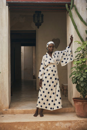 Woman wearing Kleed Blue Dots Bee Kimono in 100% handwoven Ikat cotton cream with navy polka dot pattern standing in doorway