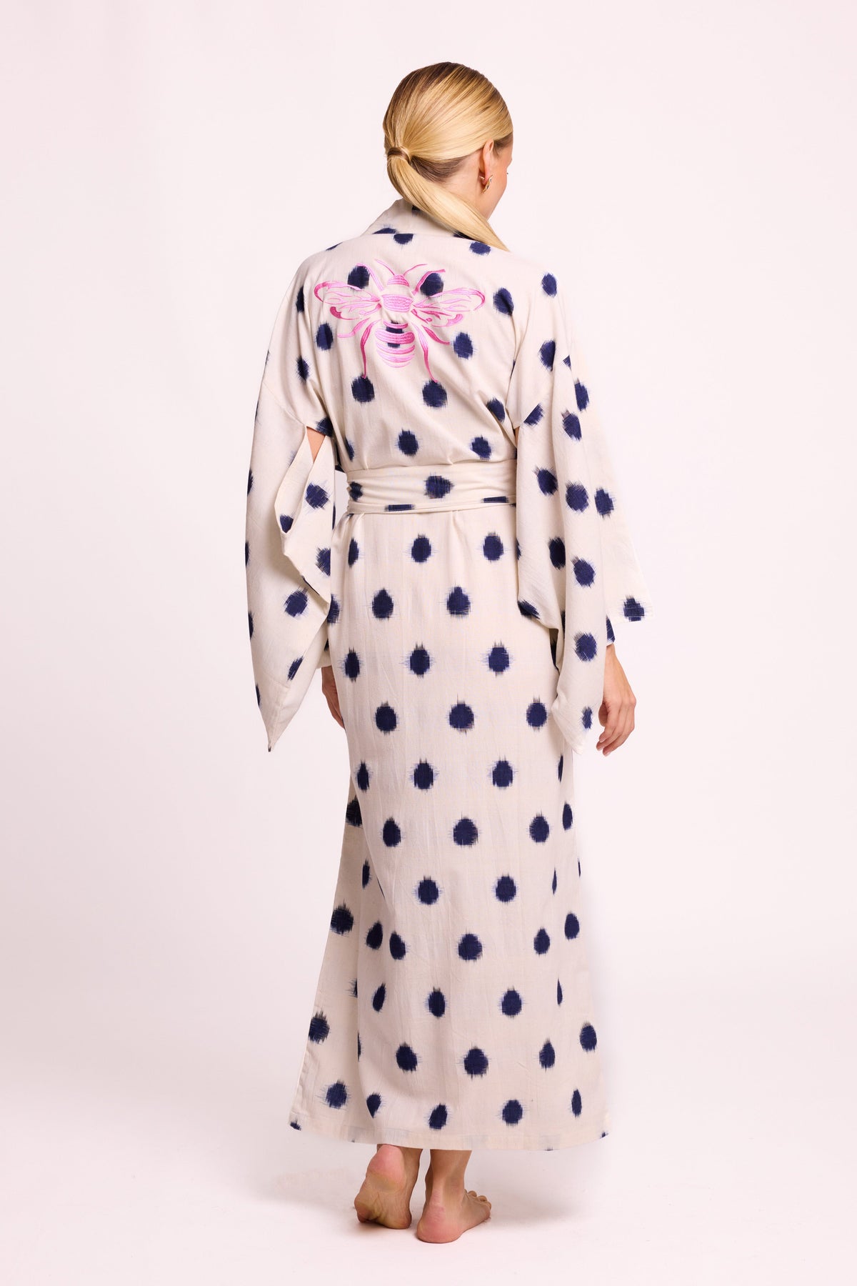 Back view of woman wearing Kleed Blue Dots Bee Kimono handwoven Ikat cotton cream navy dots with pink bee hand embroidery