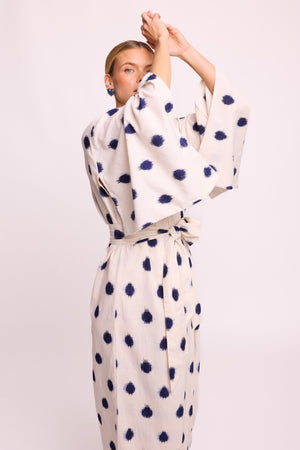 Woman wearing Kleed Blue Dots Bee Kimono in 100% handwoven Ikat cotton cream navy polka dot pattern arms raised studio