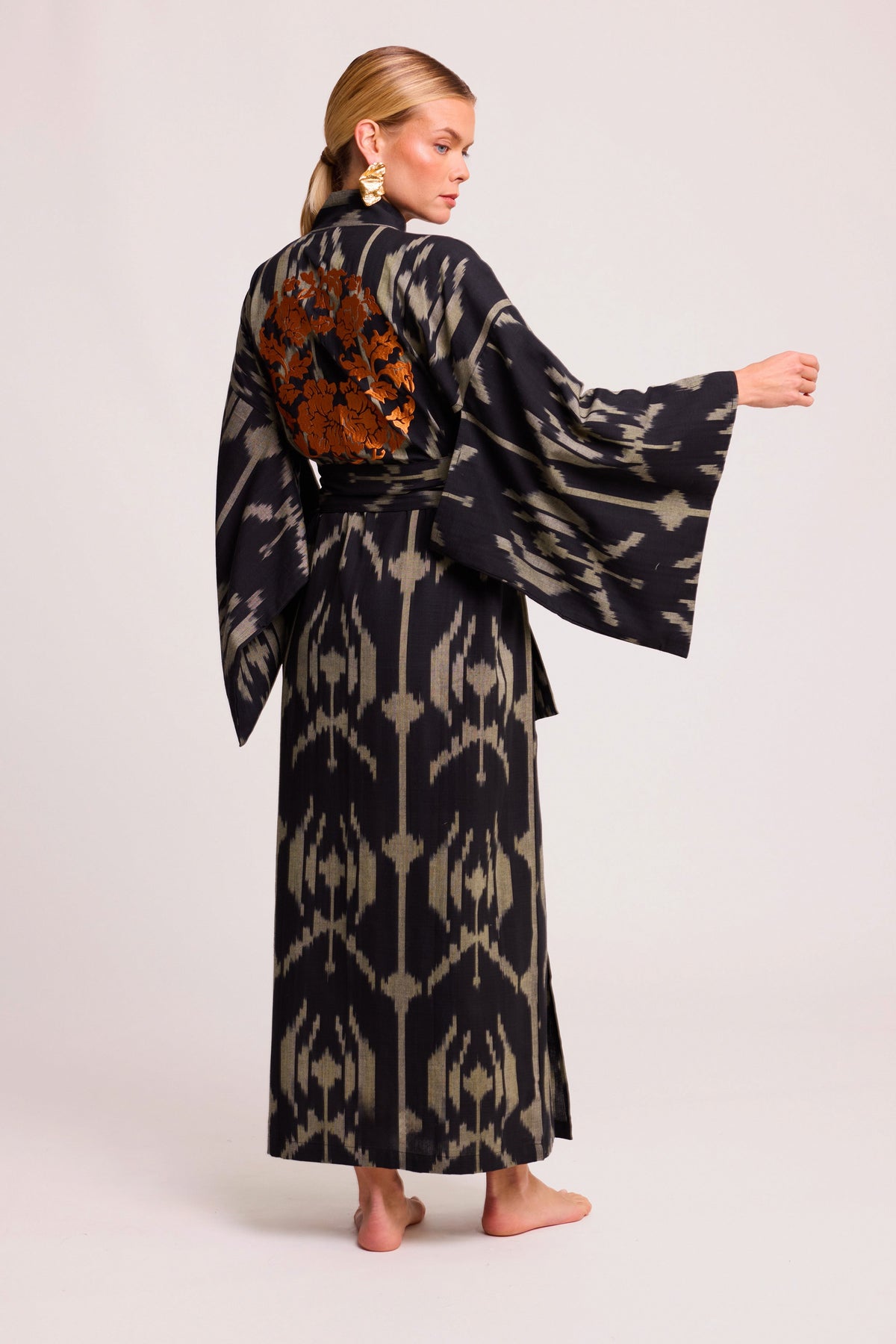 Back view of woman wearing Kleed Congo Naya Kimono handloomed Ikat cotton black khaki with orange hand embroidery detail
