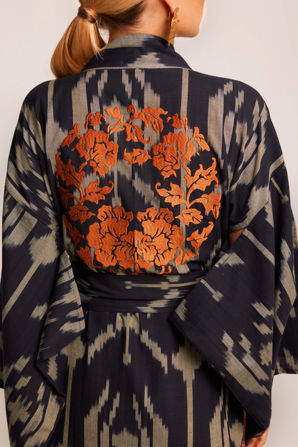 Close up of orange garland embroidery on back of Kleed Congo Naya Kimono in handloomed Ikat cotton black and khaki 
 