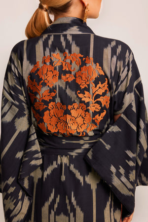 Close up of orange garland embroidery on back of Kleed Congo Naya Kimono in handloomed Ikat cotton black and khaki 
 