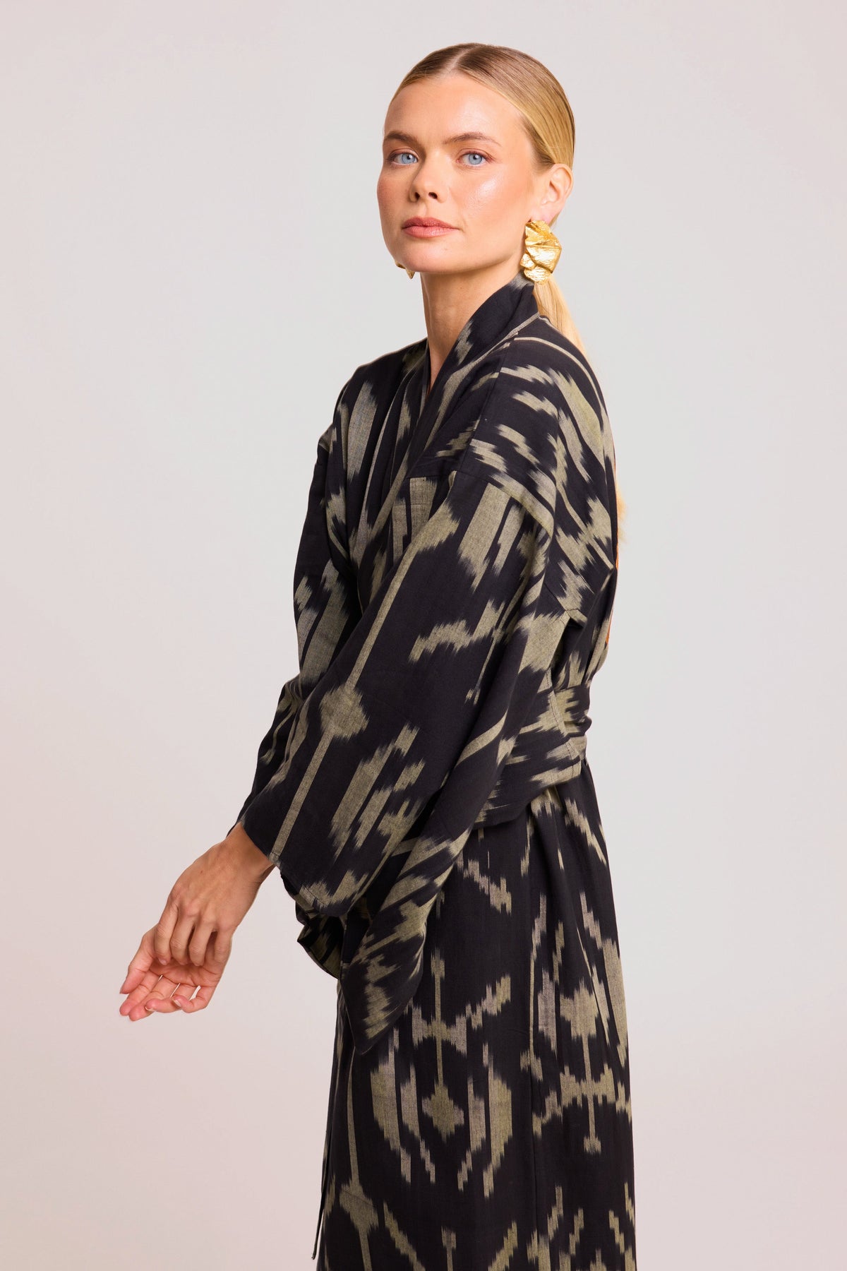 Side view of woman wearing Kleed Congo Naya Kimono in handloomed Ikat cotton black and khaki abstract pattern studio