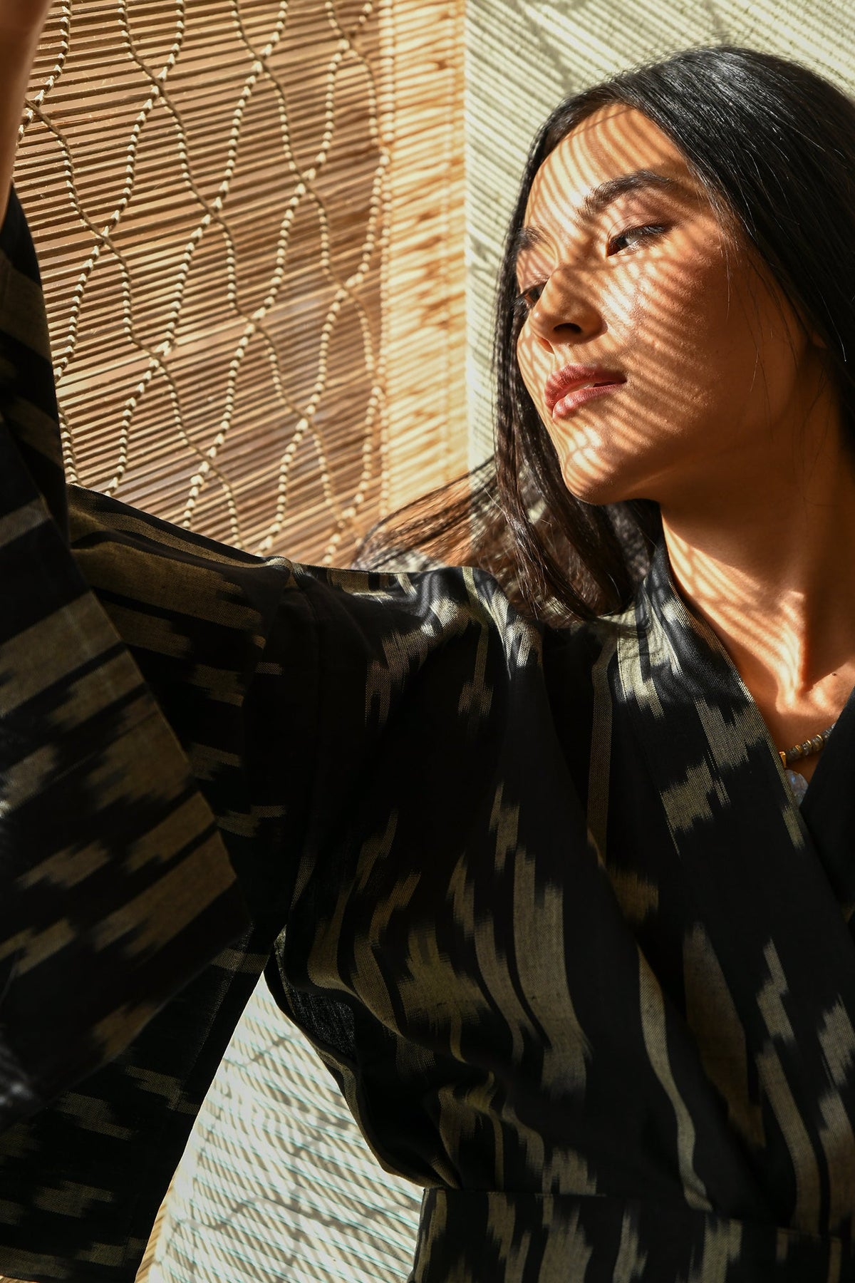 Woman in sunlight wearing Kleed Congo Naya Kimono in handloomed Ikat cotton black and khaki artisanal sustainable kimono